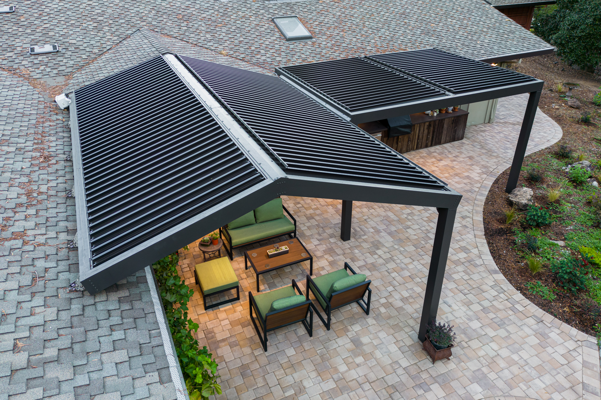 Drone shot of an angled motorized pergola installation from above, louvers partially open.