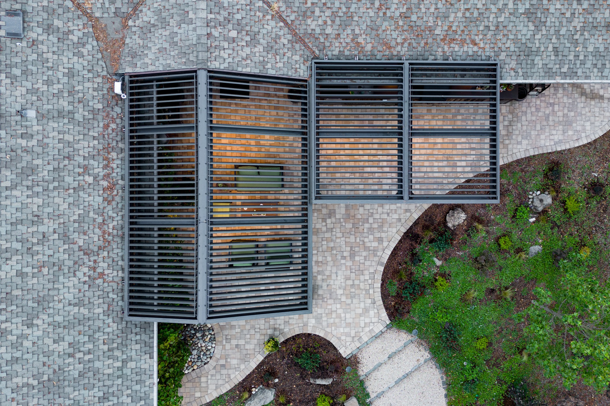 Close overhead drone detail of motorized aluminum louvers in a charcoal finish.