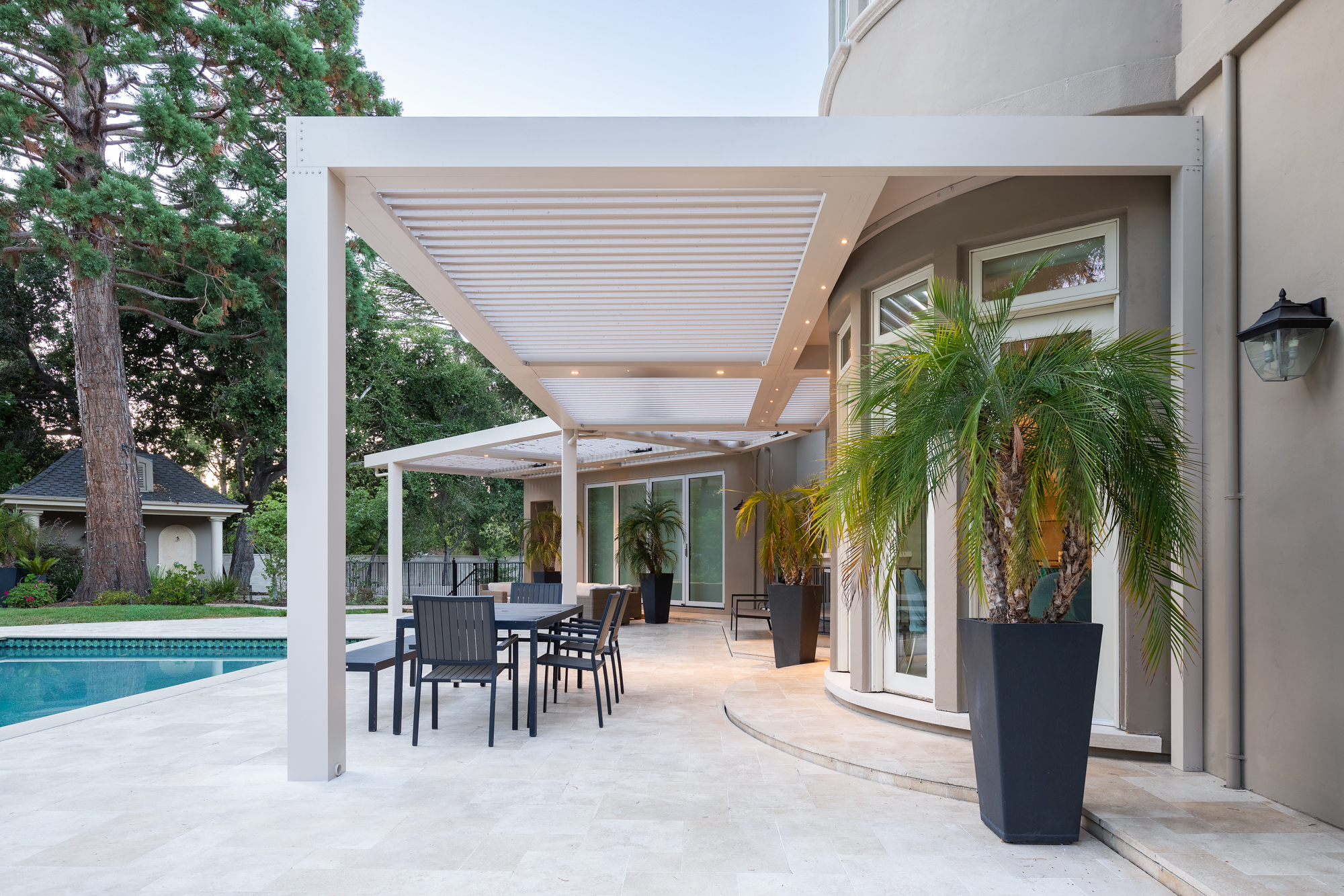 Looking up through open aluminum louvers with integrated LED downlights at golden hour.